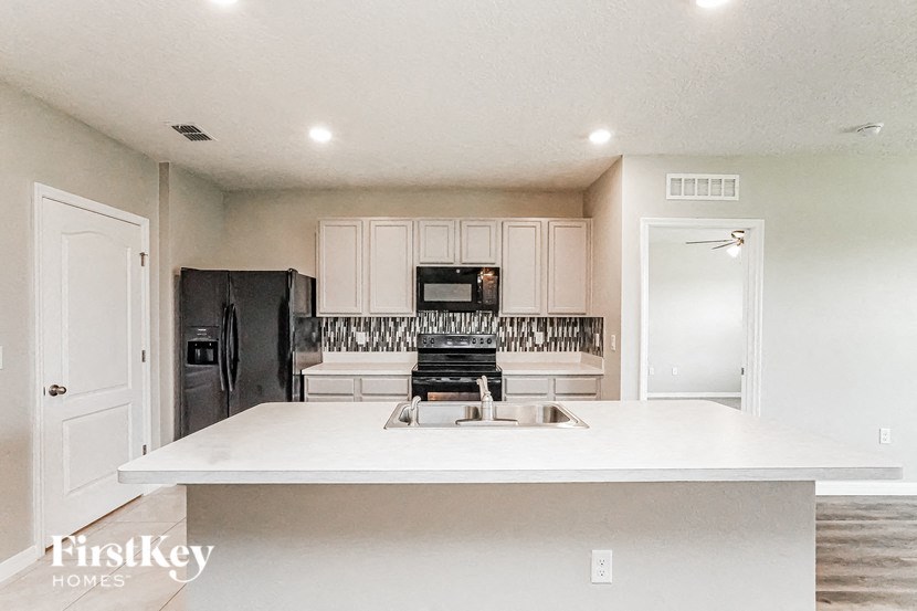 A kitchen with a black fridge and white cabinets.