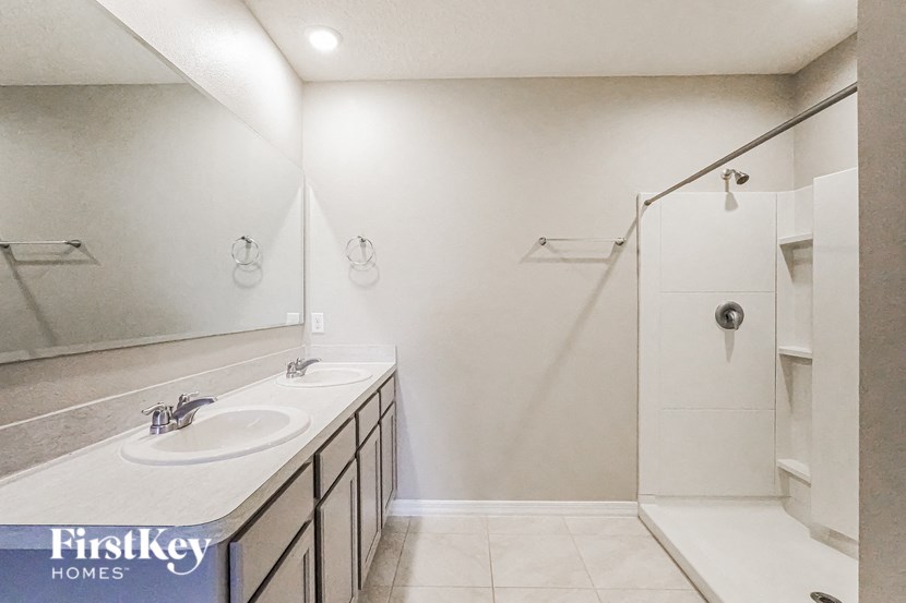 A bathroom with a sink, mirror, and shower.
