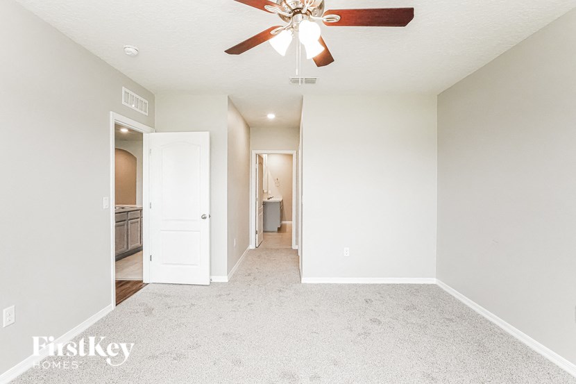 A spacious room with a ceiling fan and carpeted floor.