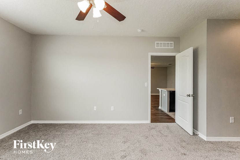A room with a carpet floor and a ceiling fan.