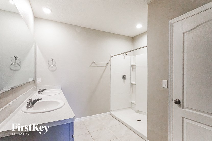 A bathroom with a sink, mirror, and shower.