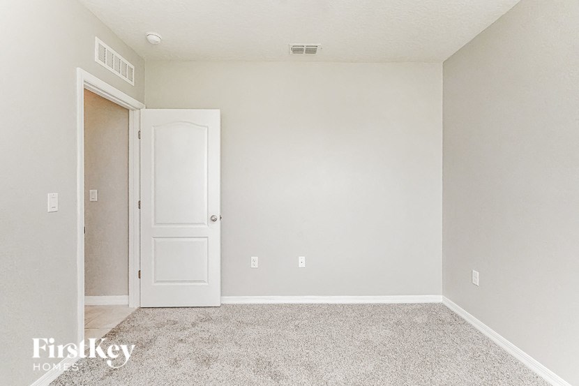 A room with a white door and a carpeted floor.