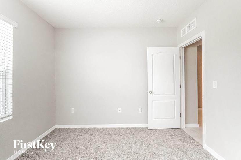 A room with a white door and a carpeted floor.