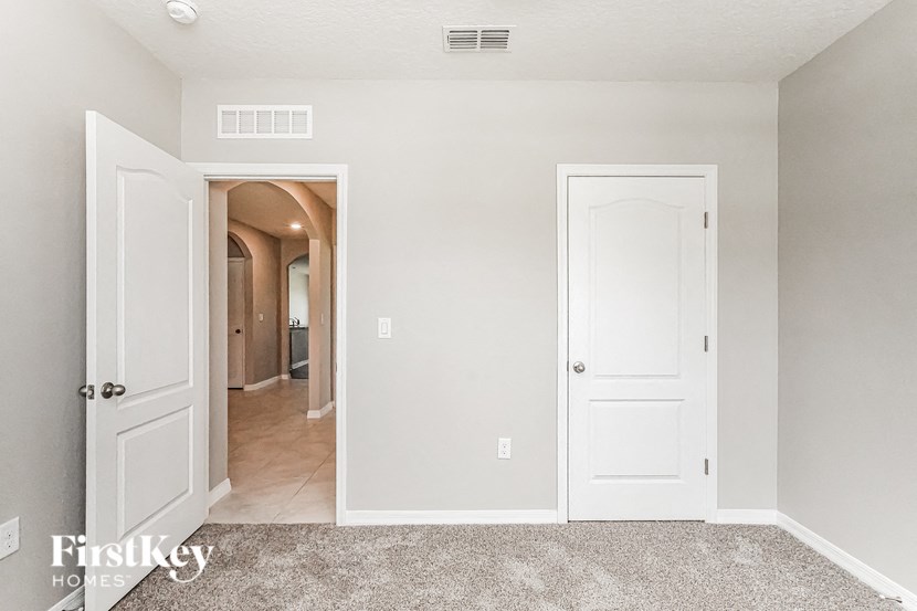 A room with a carpeted floor and two white doors, one of which is open.