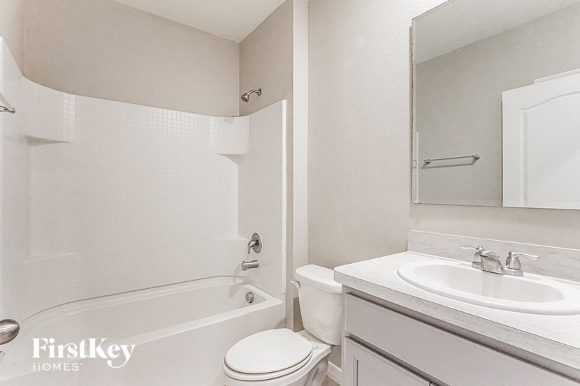 A white bathroom with a tub, toilet and sink.