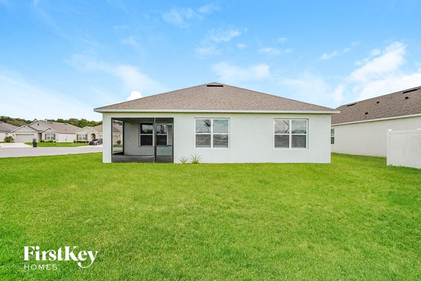 A white house with a brown roof and a green lawn in front.