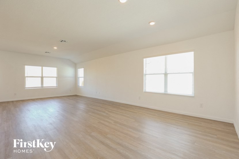 the spacious living room with wood floors and white walls