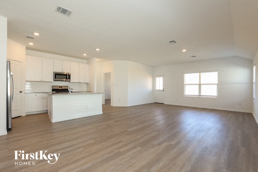 an open kitchen and living room with white cabinets and wood flooring