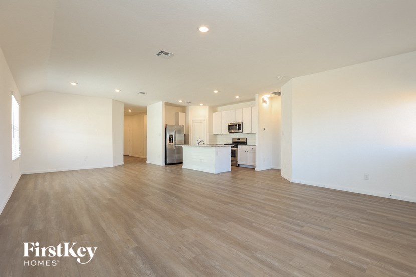 an empty living room and kitchen with white walls and wood flooring