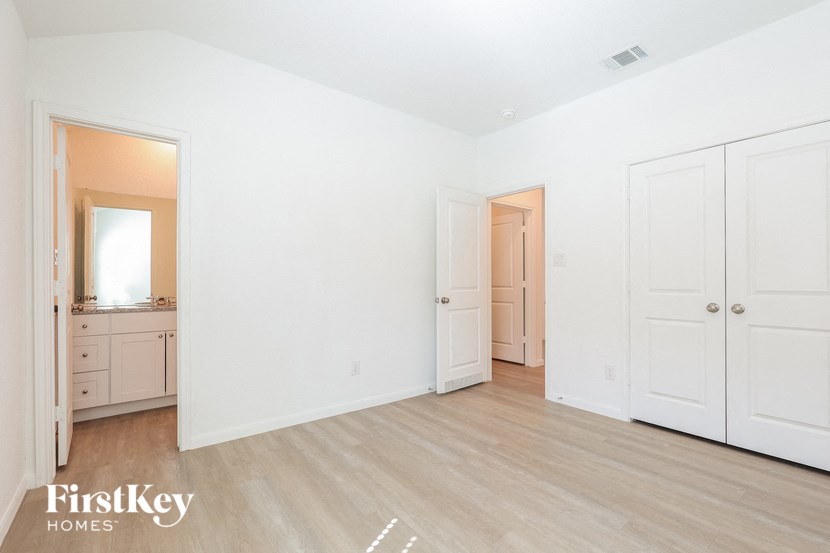 a bedroom with white walls and wooden floors and white closets