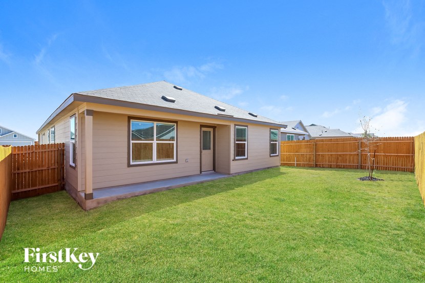 a small tan house with a yard and a wooden fence
