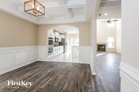 A well-lit, spacious kitchen and living room with wooden floors and a modern ceiling fan.
