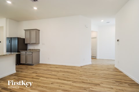 A spacious room with wooden flooring and a kitchenette.