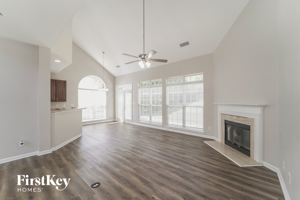 A spacious living room with a fireplace and a ceiling fan.