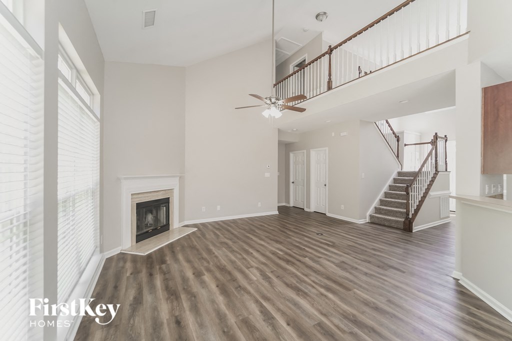 A spacious living room with a fireplace and a staircase.