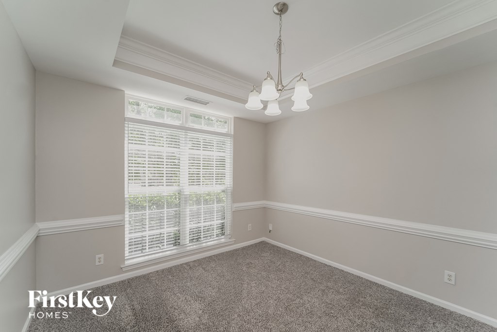 A room with a carpeted floor and a chandelier hanging from the ceiling.