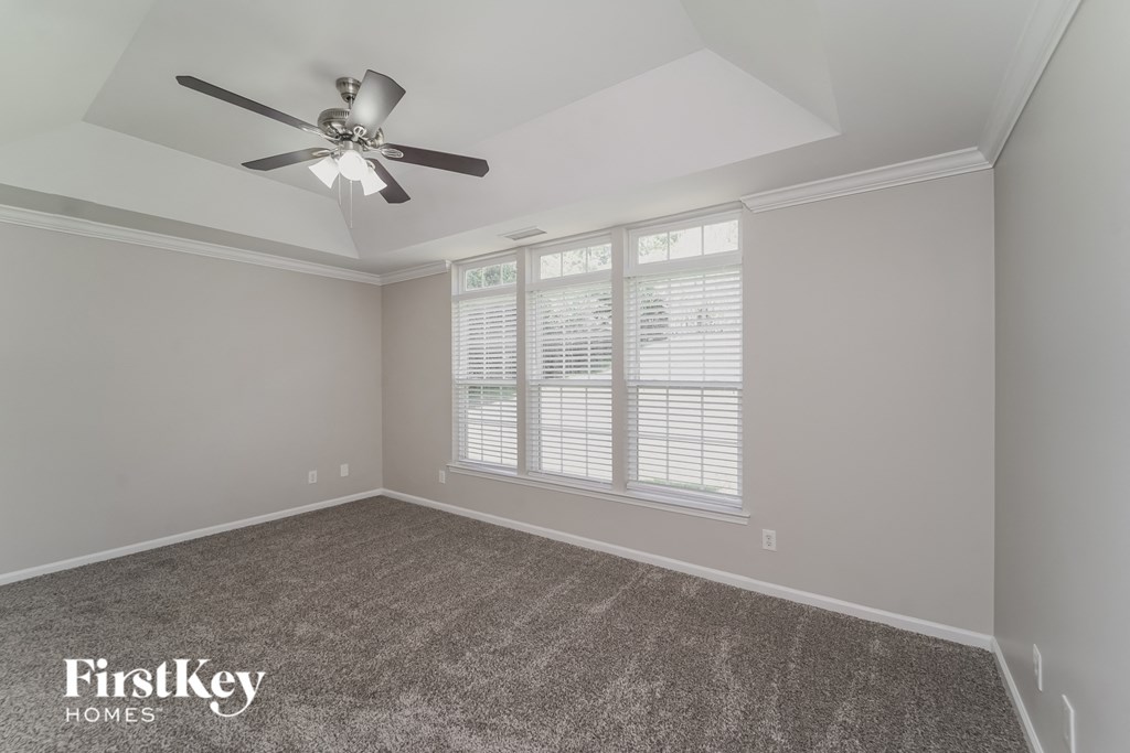 A room with a ceiling fan and a window with blinds.