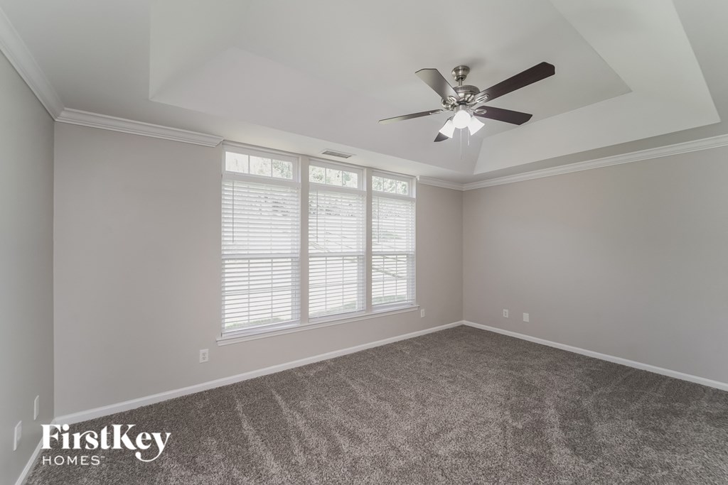 A room with a fan and carpeted floor.
