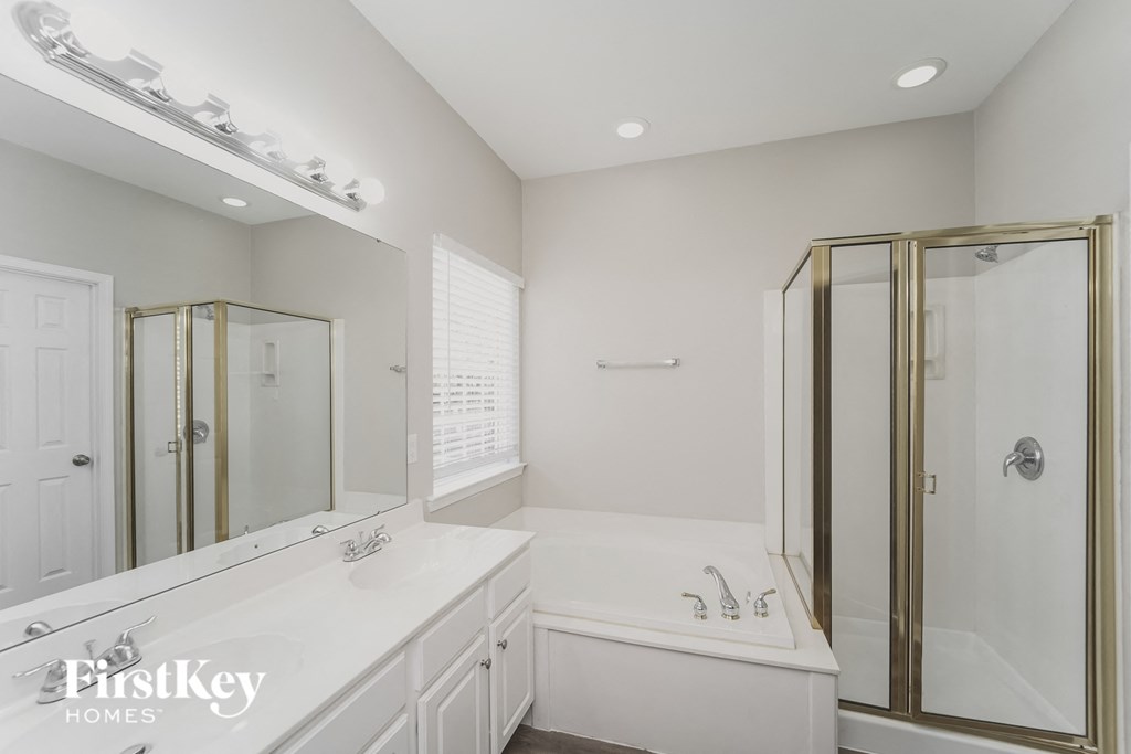 A white bathroom with a gold framed shower door.