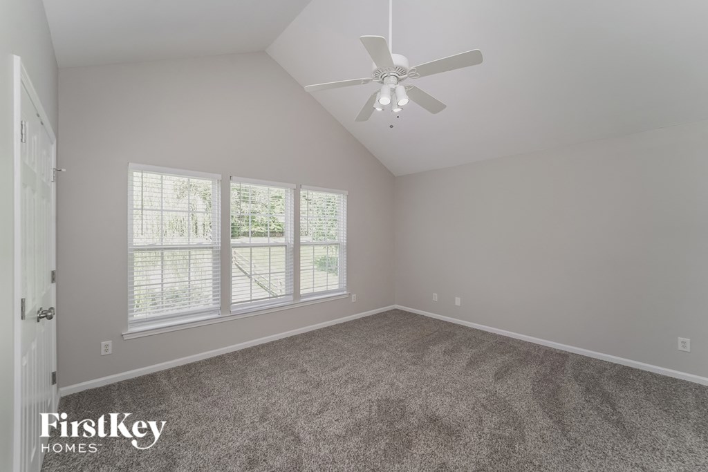 A room with a carpeted floor and a ceiling fan.
