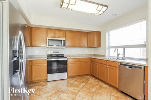A kitchen with wooden cabinets and a tile floor.