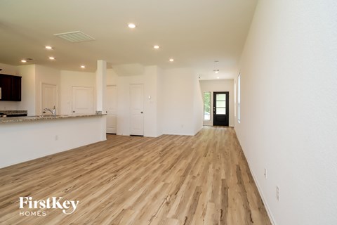 A spacious room with wooden flooring and white walls.
