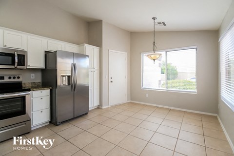 A kitchen with a refrigerator, microwave, oven and cabinets.