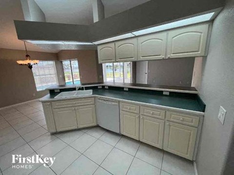 A kitchen with white cabinets and a black countertop.