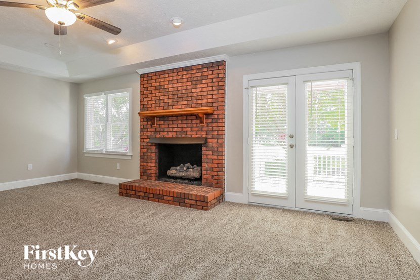 a living room with a brick fireplace and doors
