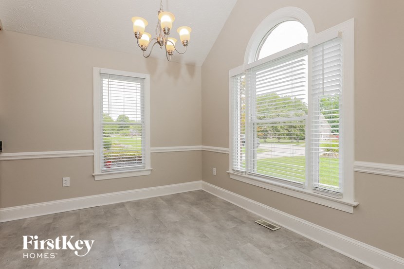 an empty room with large windows and a chandelier