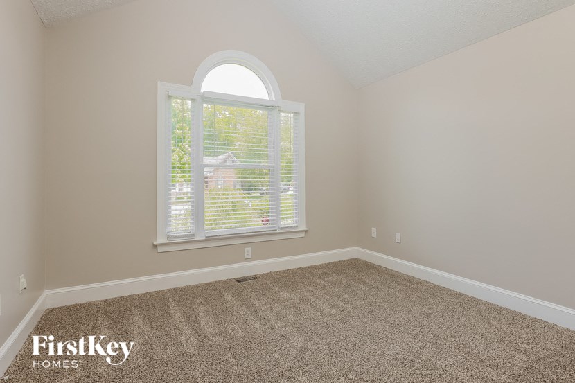 an empty bedroom with a large window and carpet