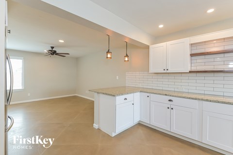 A kitchen with white cabinets and a fan on the ceiling.