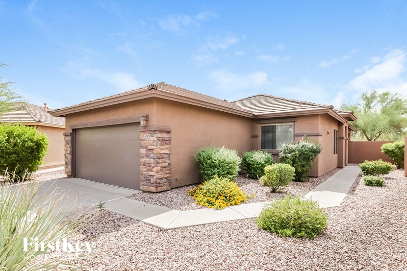 A house with a brown roof and a gravel driveway.