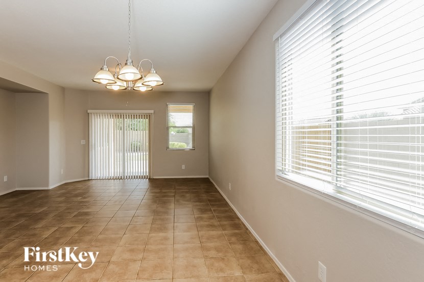 A spacious room with a chandelier and a window with blinds.