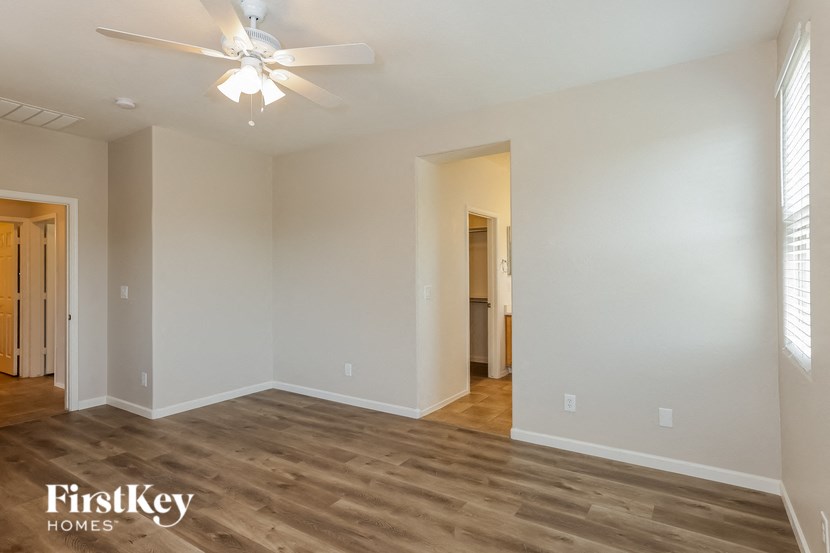 A spacious room with a ceiling fan and wooden flooring.
