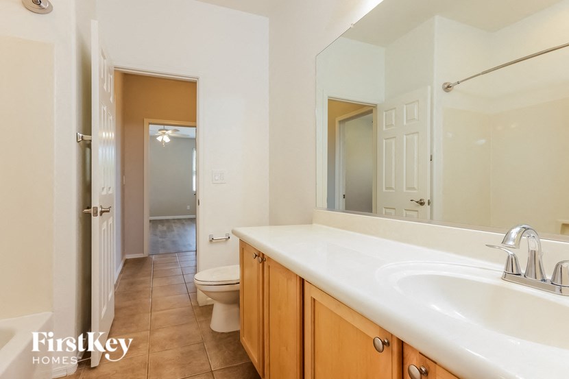 A bathroom with a toilet, sink and mirror.
