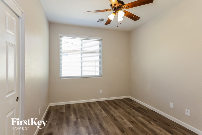 A room with a ceiling fan and a window with blinds.