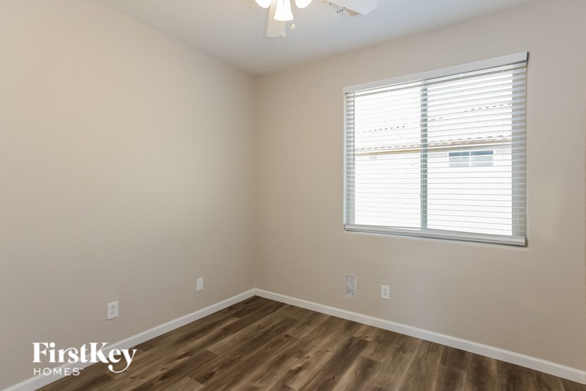 A room with a window covered by white blinds and a wooden floor.
