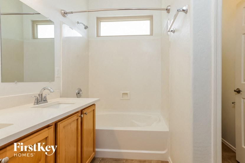 A white bathroom with a tub, sink, and mirror.