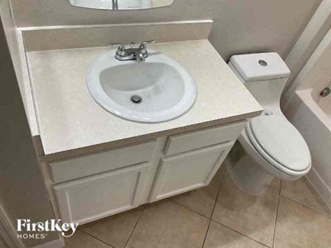 A white sink with a silver faucet is on a countertop in a bathroom.
