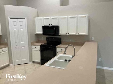 A kitchen with white cabinets and a black stove top oven.