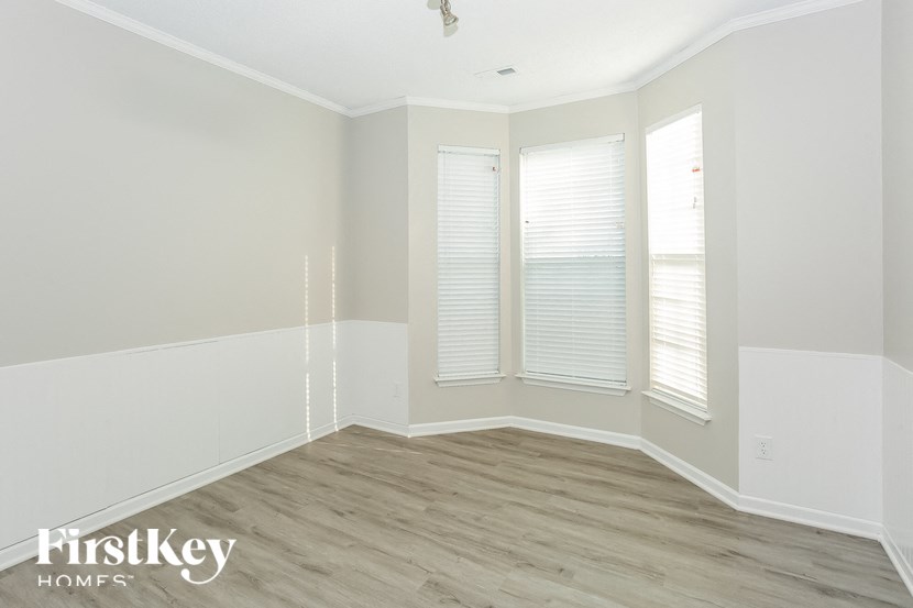 the living room of a home with white walls and wood floors