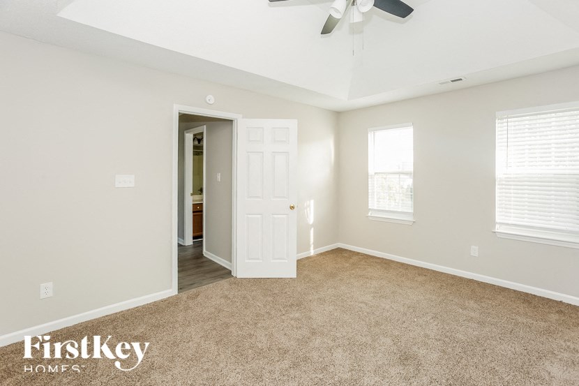 an empty living room with a white door and a ceiling fan