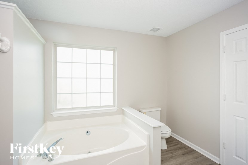 a white bathroom with a large white tub and a window