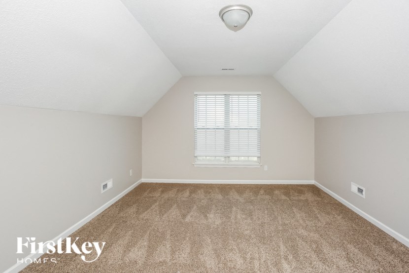 a spacious bedroom with carpeting and a window
