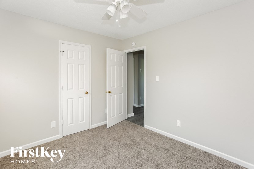 a bedroom with two doors and a carpeted floor and a ceiling fan