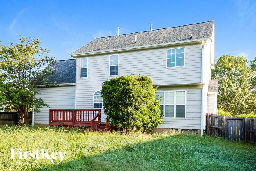a backyard with a wooden bench in front of a white house