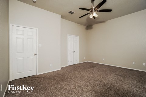 the living room of a home with carpet and a ceiling fan