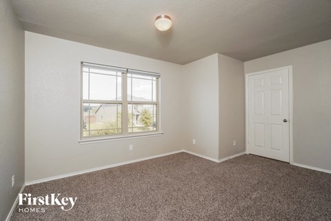 a bedroom with carpet and a window and a door