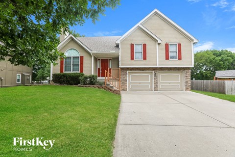 a beige house with red doors and a driveway